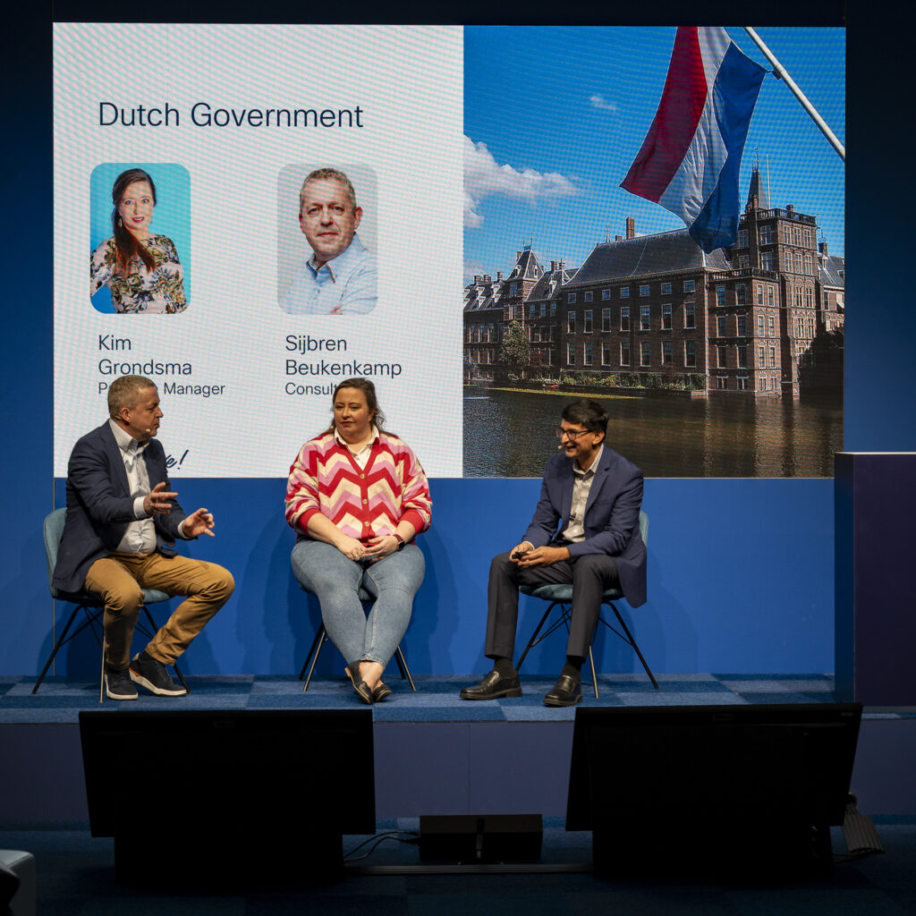 Sijbren Beukenkamp op het podium van Cisco Live, naast Cisco's slide 'Dutch Government' met zijn naam erop